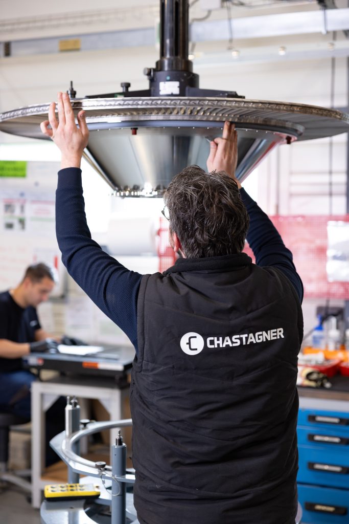 Opérateur Chastagner réalisant l’assemblage d’un sous-ensemble aéronautique de grande dimension dans un atelier, avec positionnement précis de la pièce sur un poste d’intégration.