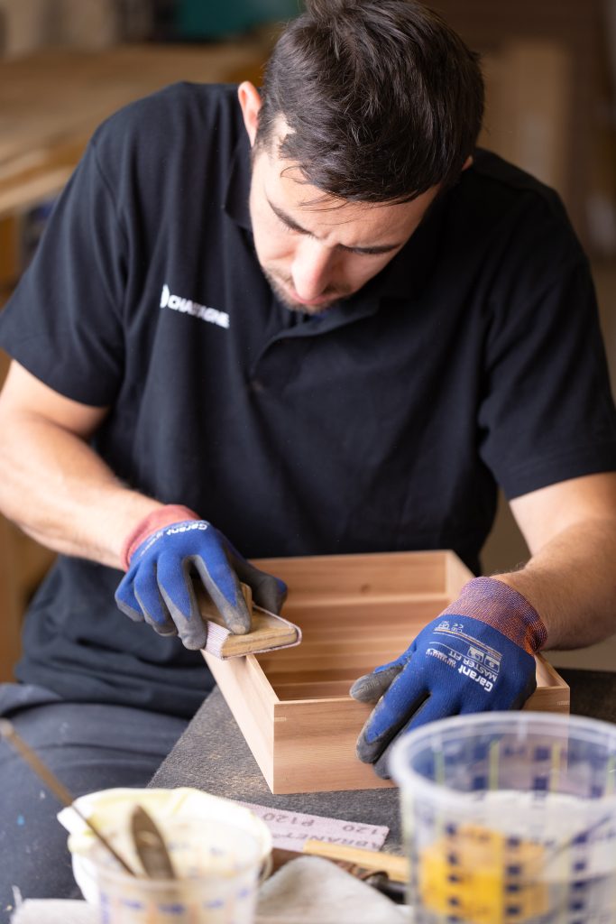 Collaborateur Chastagner réalisant un assemblage bois en atelier, illustrant le savoir-faire manuel et la précision de finition pour des produits haut de gamme.