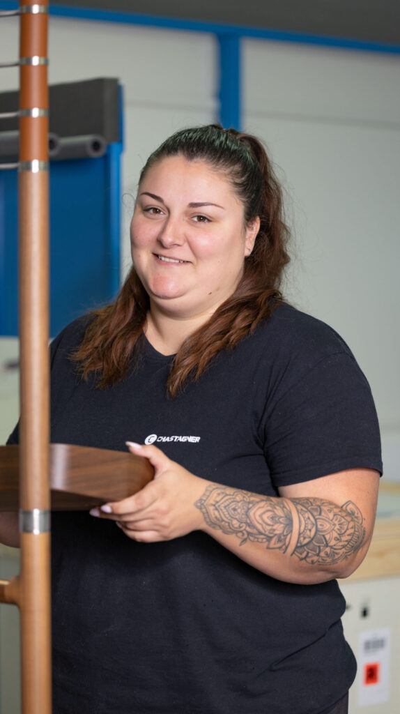 Collaboratrice Chastagner tenant et ajustant un élément en bois haut de gamme en atelier, dans le cadre d’une opération d’intégration et d’assemblage de produit d’exception.